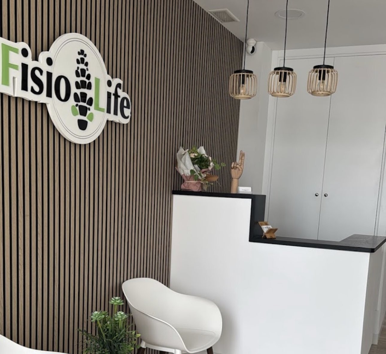 Recepción de FisioLife Conil, con el rótulo de la clínica sobre pared de listones de madera