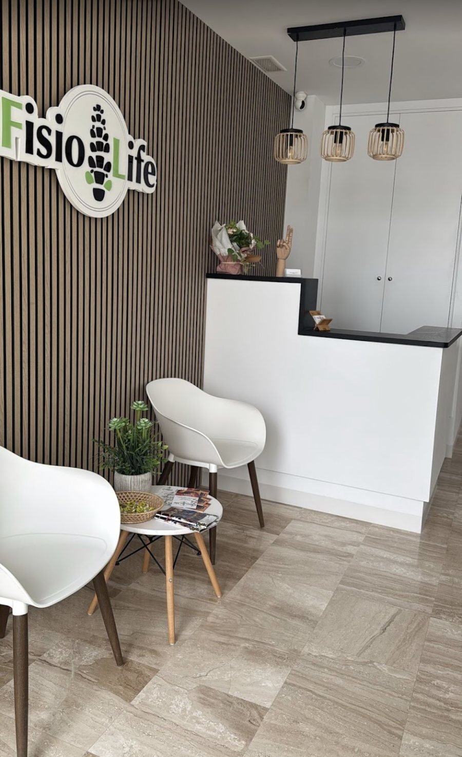 Sala de espera de FisioLife Conil con butacas y el logotipo de la clínica en la pared